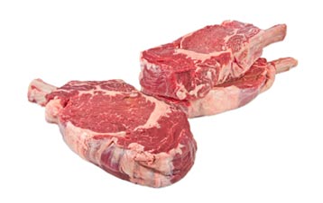 3 raw, grass-fed, cowboy steaks, 1 in the foreground, 2 stacked in the background  